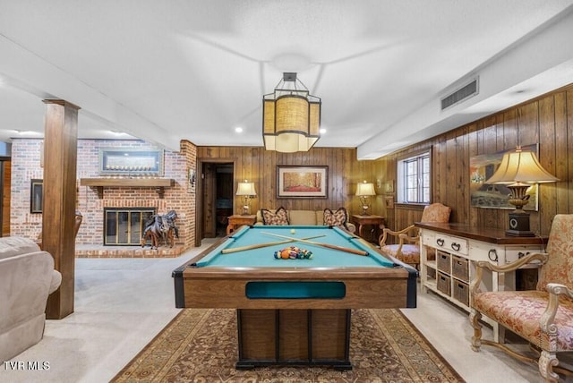 rec room with wood walls, a brick fireplace, brick wall, billiards, and light carpet