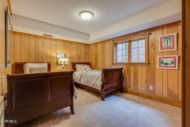 carpeted bedroom with wood walls and a textured ceiling