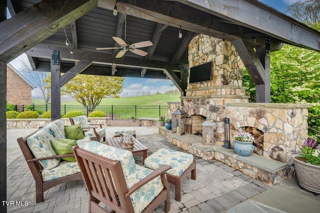 view of patio / terrace featuring an outdoor stone fireplace, ceiling fan, and a gazebo