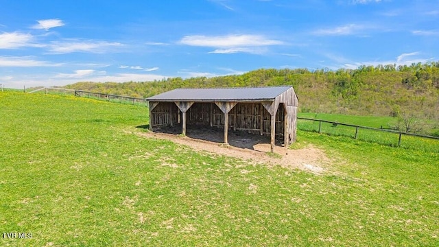 view of outbuilding featuring a rural view and a lawn