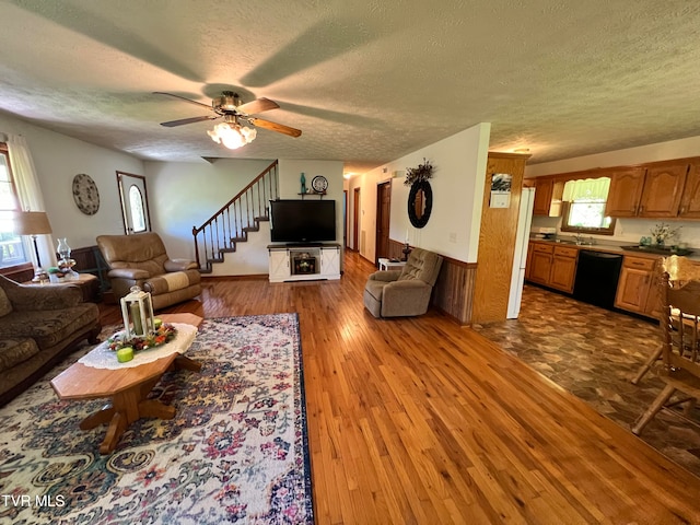 living room featuring wood-type flooring, ceiling fan, sink, and a textured ceiling