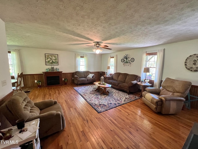 living room featuring hardwood / wood-style flooring, ceiling fan, and a textured ceiling