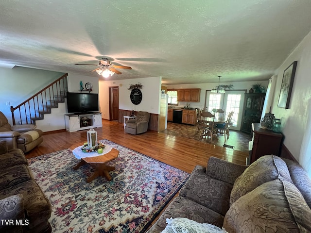 living room featuring hardwood / wood-style flooring, ceiling fan, and a textured ceiling