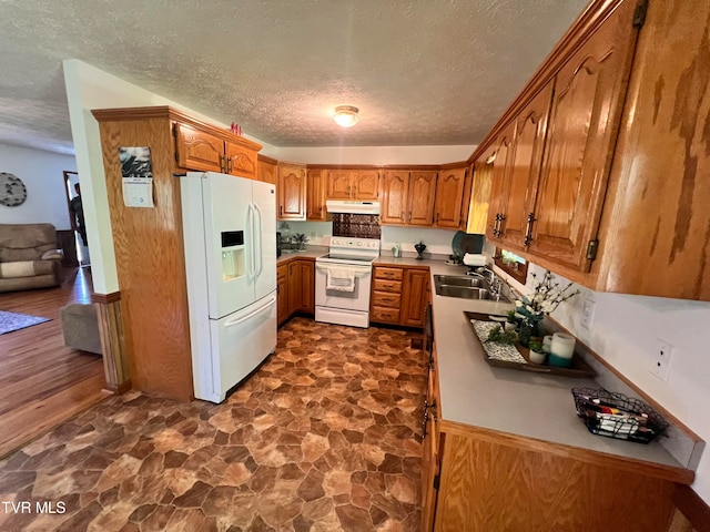 kitchen with sink, white appliances, dark tile flooring, and a textured ceiling