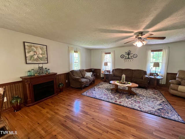 living room with wood-type flooring, ceiling fan, and a textured ceiling