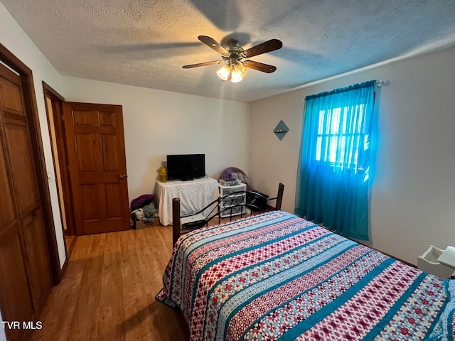 bedroom featuring wood-type flooring, a textured ceiling, and ceiling fan