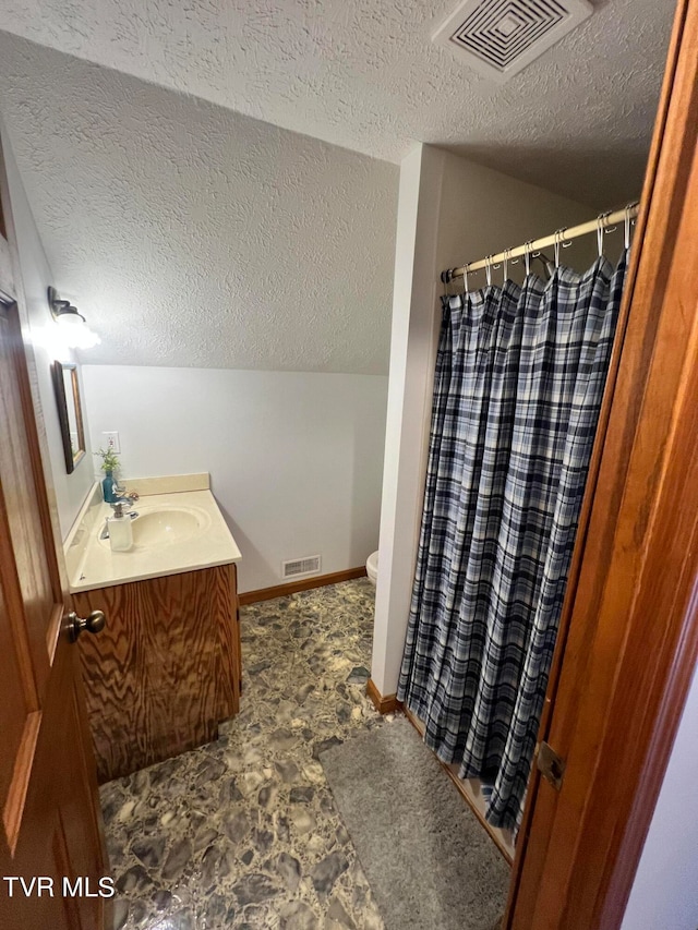 bathroom featuring a textured ceiling, vanity, toilet, and tile flooring