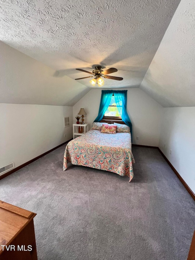 bedroom with ceiling fan, vaulted ceiling, dark carpet, and a textured ceiling