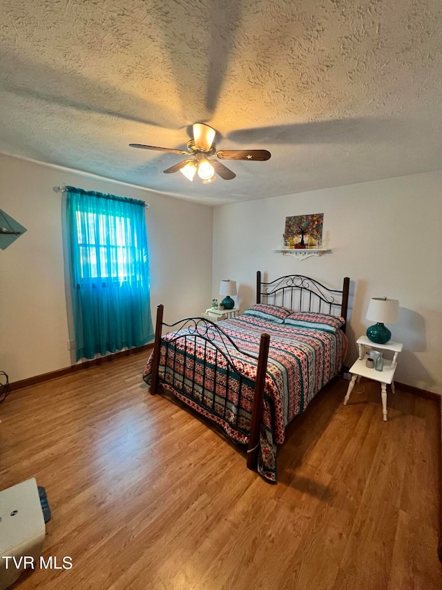 bedroom featuring hardwood / wood-style flooring, ceiling fan, and a textured ceiling