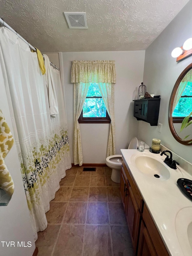 bathroom featuring a wealth of natural light, toilet, tile floors, and large vanity