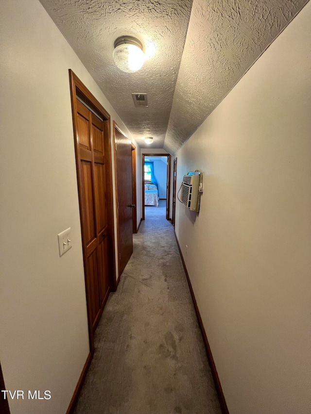 hall with lofted ceiling, carpet flooring, and a textured ceiling