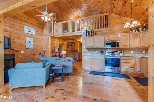 kitchen with stainless steel appliances, high vaulted ceiling, light brown cabinetry, and light hardwood / wood-style floors