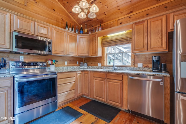 kitchen with stainless steel appliances, lofted ceiling, light stone counters, sink, and hardwood / wood-style flooring