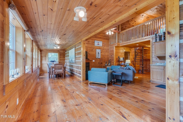 living room with hardwood / wood-style floors, wooden walls, ceiling fan, and wood ceiling