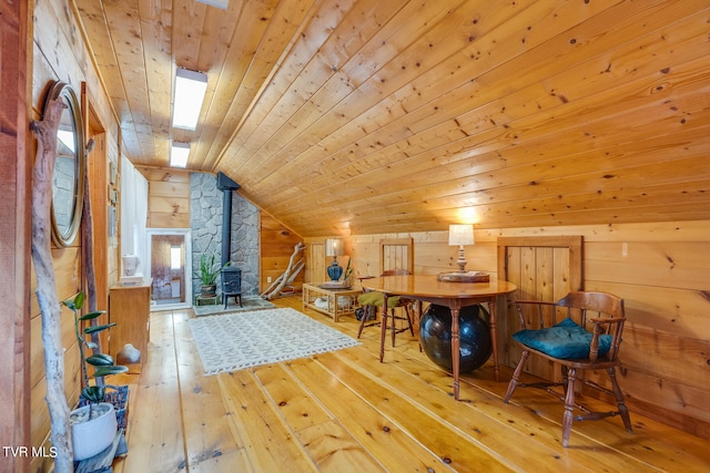 bedroom with a wood stove, wood walls, wood ceiling, light wood-type flooring, and lofted ceiling