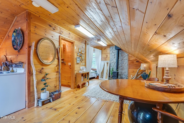 dining space with wooden ceiling, hardwood / wood-style flooring, wooden walls, a wood stove, and vaulted ceiling