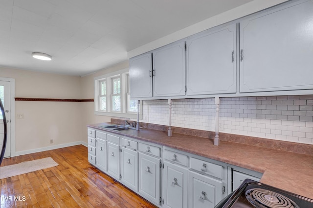 kitchen featuring backsplash, gray cabinetry, sink, and light wood-type flooring