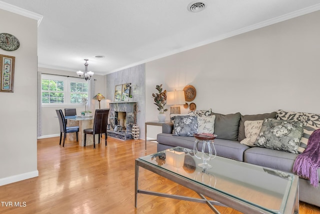 living room with an inviting chandelier, ornamental molding, and light hardwood / wood-style flooring