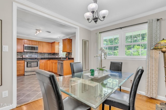 dining room with a chandelier, sink, ornamental molding, and light tile floors