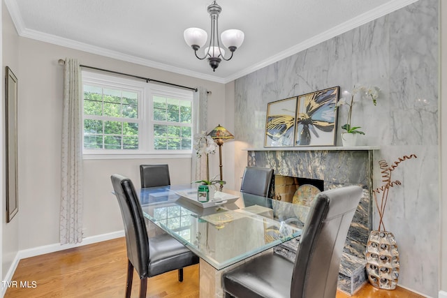 dining room featuring a chandelier, ornamental molding, light wood-type flooring, and a high end fireplace