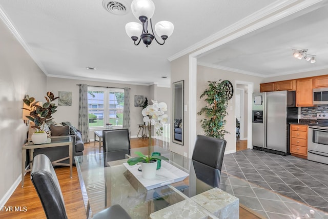 dining room featuring crown molding, dark tile floors, and an inviting chandelier