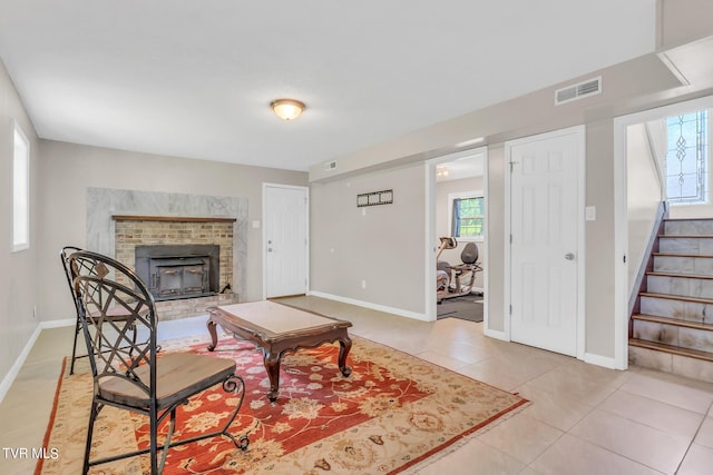 tiled living room featuring a brick fireplace