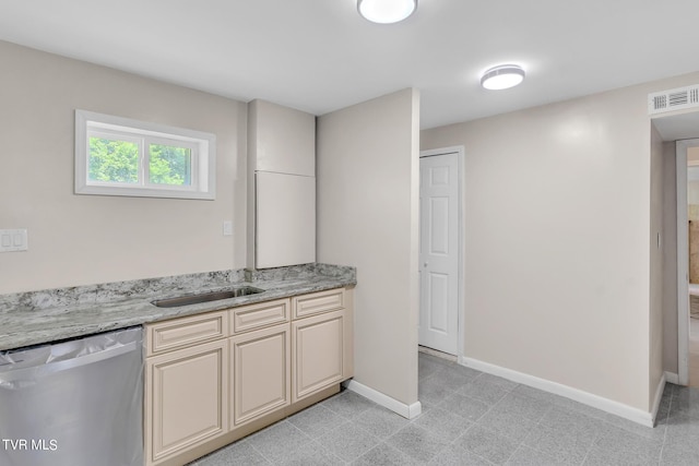 kitchen featuring cream cabinetry, dishwasher, light stone countertops, sink, and light tile floors