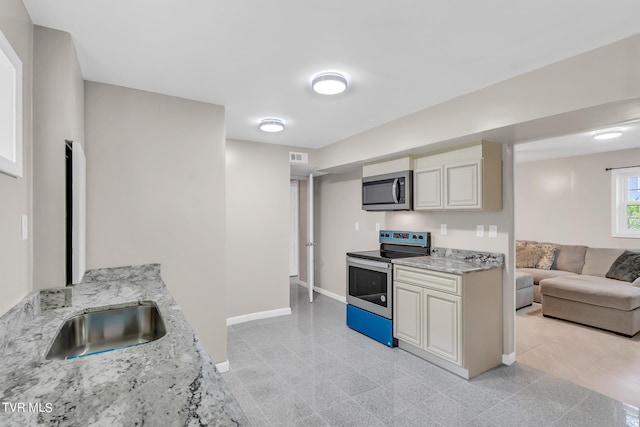 kitchen featuring sink, light stone countertops, light tile flooring, and stainless steel appliances