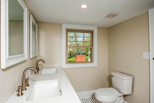 bathroom featuring tile floors, toilet, and dual sinks