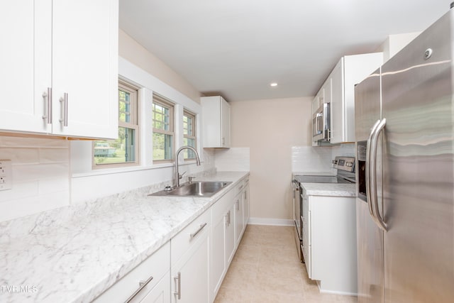 kitchen featuring white cabinets, sink, light tile flooring, backsplash, and stainless steel appliances