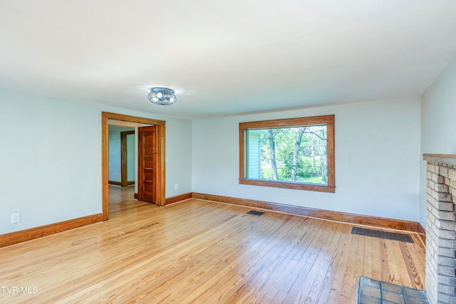 unfurnished living room featuring light hardwood / wood-style flooring and a brick fireplace