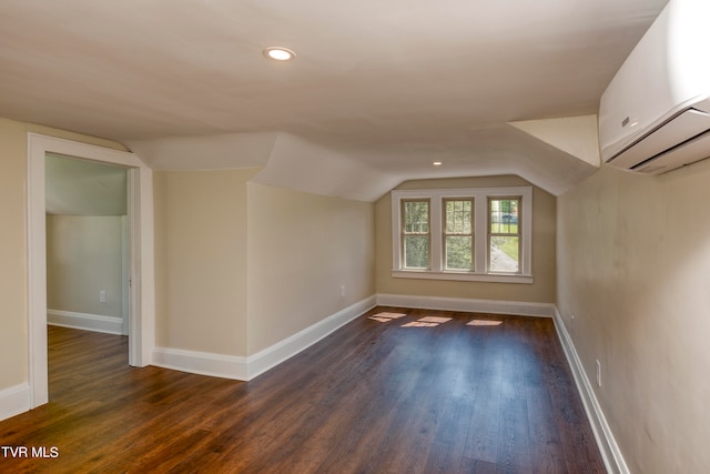 additional living space featuring hardwood / wood-style flooring, a wall mounted AC, and vaulted ceiling