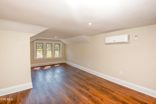 additional living space featuring lofted ceiling, dark wood-type flooring, and a wall mounted AC