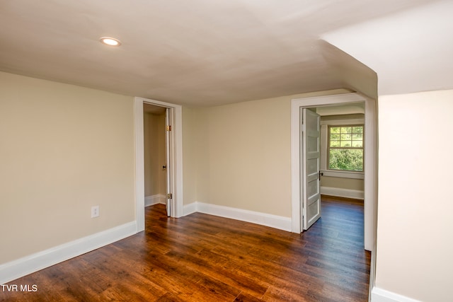 unfurnished room with dark hardwood / wood-style floors and lofted ceiling