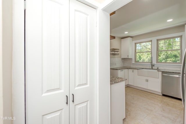 kitchen featuring white cabinets, dishwasher, tasteful backsplash, and light stone countertops