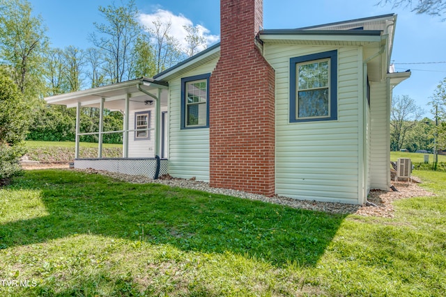 rear view of house with central AC unit and a yard