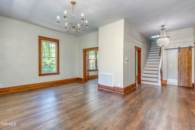 unfurnished room with an inviting chandelier, a barn door, and dark hardwood / wood-style floors