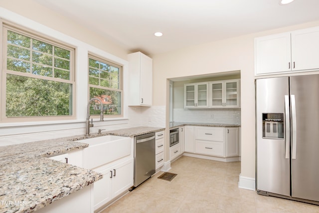 kitchen featuring backsplash, stainless steel appliances, white cabinets, and light tile floors