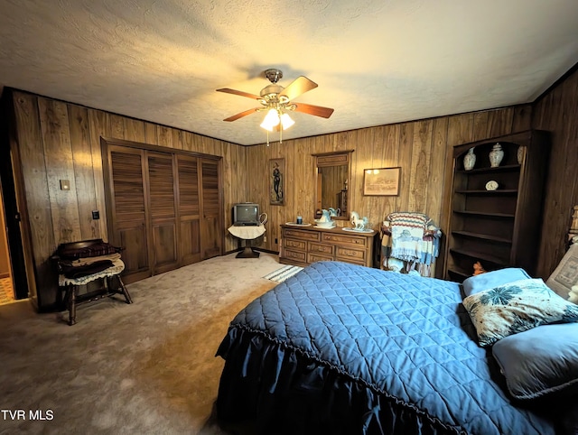 bedroom with wooden walls, a closet, carpet, a textured ceiling, and ceiling fan