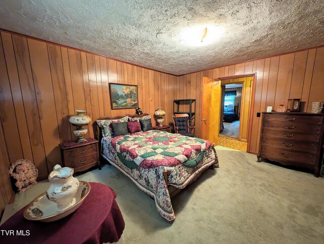 bedroom featuring wood walls, a textured ceiling, and carpet flooring