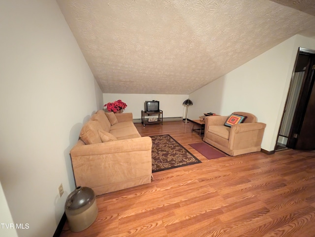 living room with a textured ceiling, lofted ceiling, and hardwood / wood-style floors