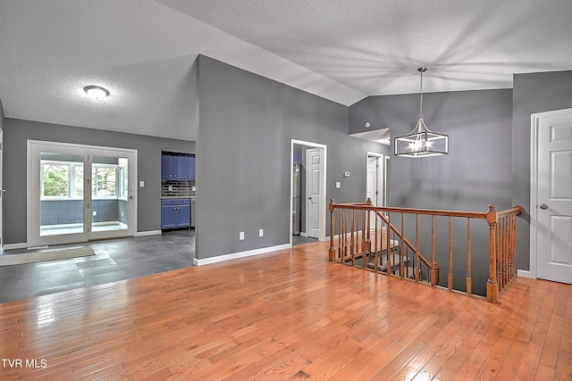 unfurnished room featuring a chandelier, wood-type flooring, and vaulted ceiling