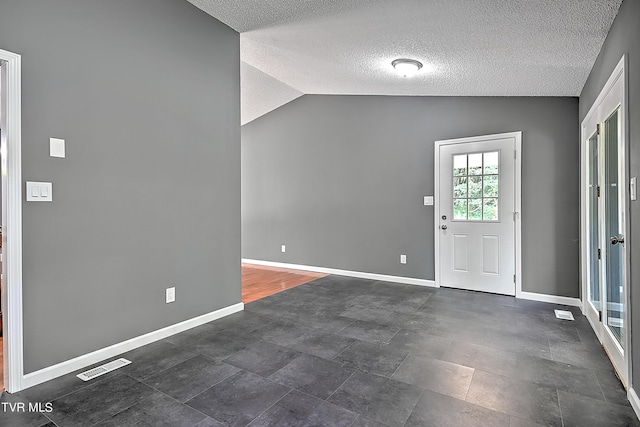 foyer entrance featuring a textured ceiling and vaulted ceiling