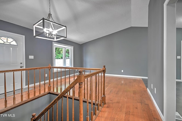 hall featuring hardwood / wood-style floors, a notable chandelier, and vaulted ceiling