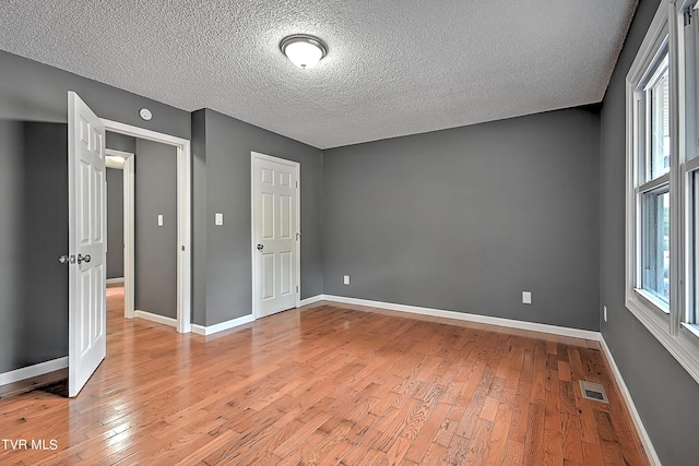 unfurnished bedroom with light hardwood / wood-style flooring and a textured ceiling