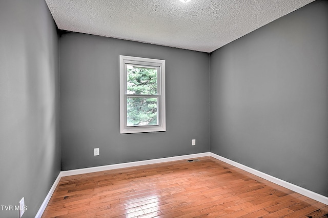 spare room with a textured ceiling and light wood-type flooring