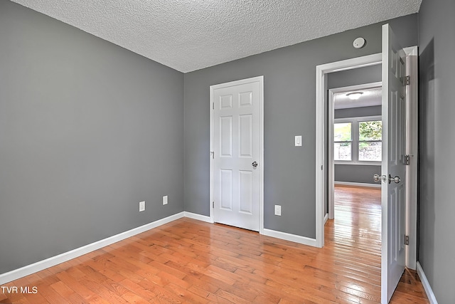 unfurnished bedroom featuring a textured ceiling and light hardwood / wood-style flooring