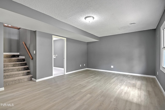 basement with light wood-type flooring and a textured ceiling