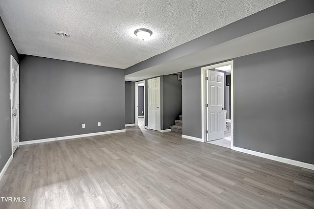 spare room with a textured ceiling and light hardwood / wood-style flooring