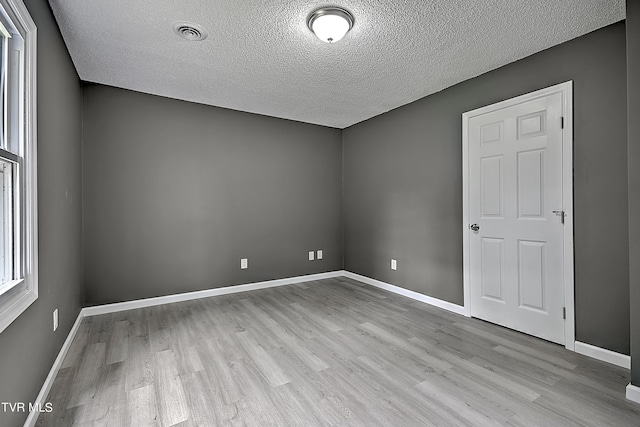 spare room featuring a textured ceiling and light wood-type flooring